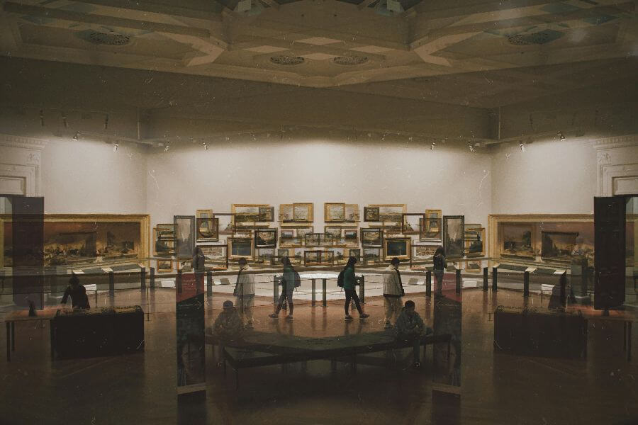 People viewing paintings in an art museum gallery